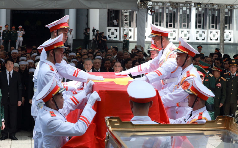 Linh cữu Tổng Bí thư Nguyễn Phú Trọng được đặt trang trọng lên đại xa gắn pháo kéo, được phủ Quốc kỳ đỏ thắm và lồng khung kính theo nghi thức cao nhất.

