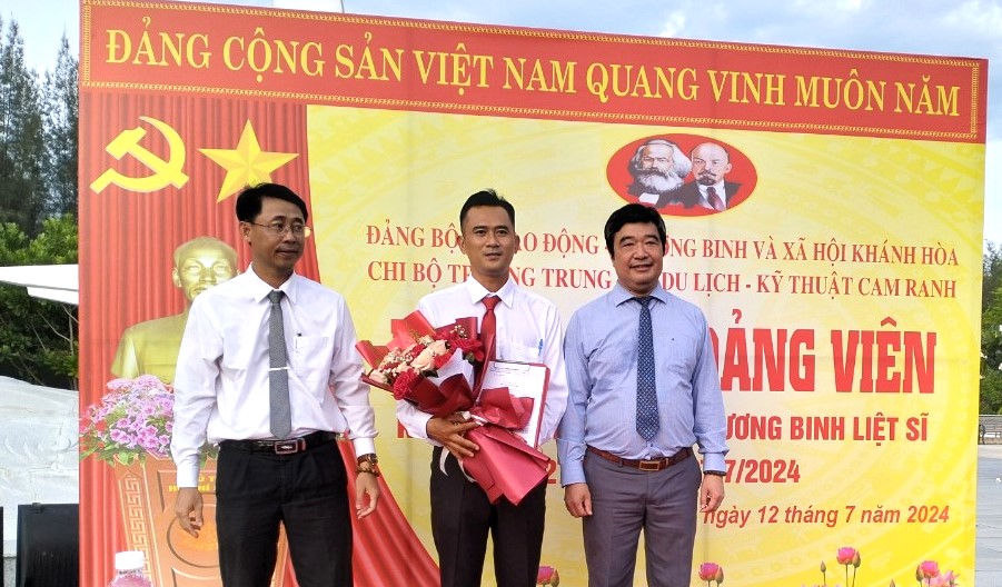 Ông Trịnh Văn Mơ -  Phó Bí thư Đảng ủy kiêm Trưởng Ban Tổ chức Đảng ủy Khối các cơ quan tỉnh (bên phải) và ông Tạ Hồng Quang - Bí thư Đảng ủy, Giám đốc Sở Lao động - Thương binh và Xã hội trao quyết định, tặng hoa chúc mừng đảng viên mới.