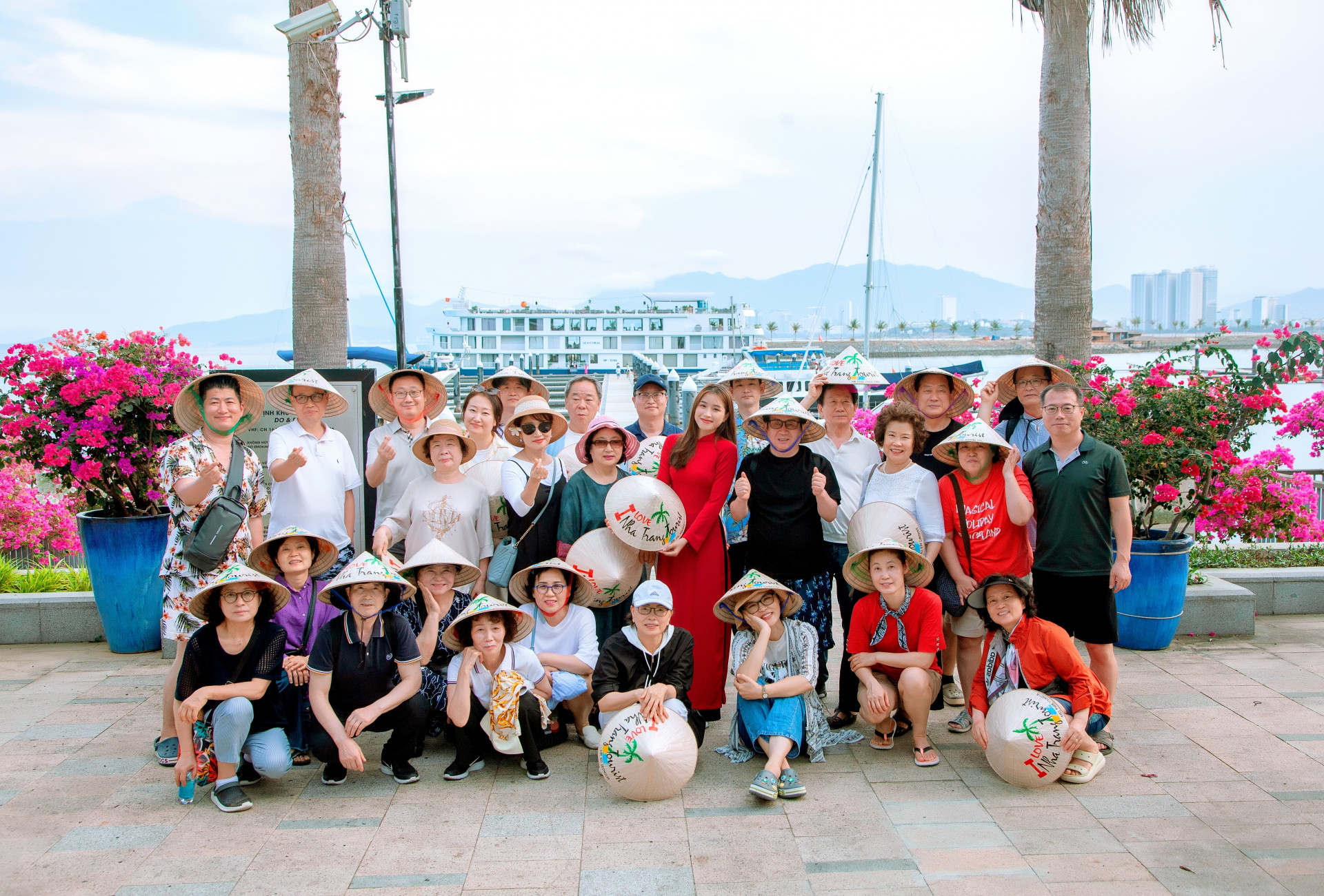 Korean tourists taking souvenir photos with traditional Vietnamese conical hats when traveling in Nha Trang.