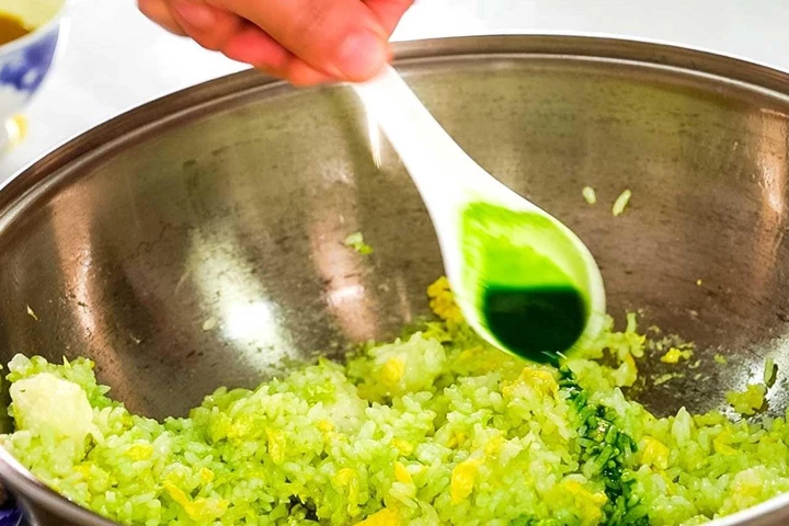 Nên cho nước ép rau vào từ từ để tránh cơm bị dính. (Ảnh: Sohu)