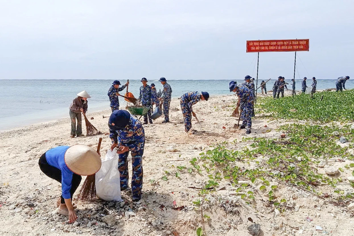 Cán bộ, chiến sĩ và người dân đảo Sinh Tồn tham gia vệ sinh bờ biển.