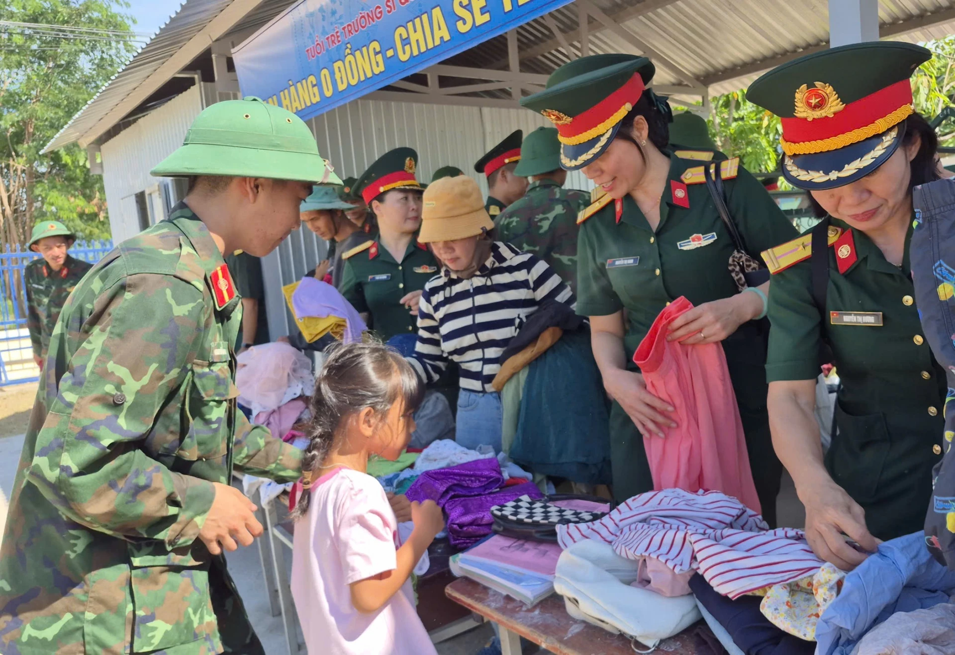 Cán bộ chiến sĩ hỗ trợ một em bé chọn áo quần tại gian hàng o đồng.