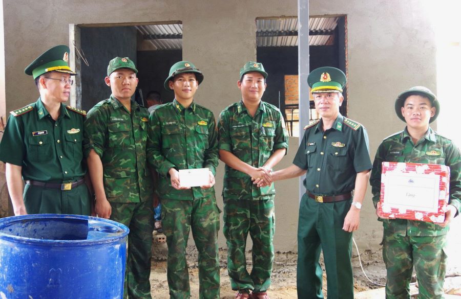 Đại tá Phan Thăng Long tặng quà động viên cán bộ, chiến sĩ đang hỗ trợ xây dựng nhà cho gia đình ông Mấu Hoành.
