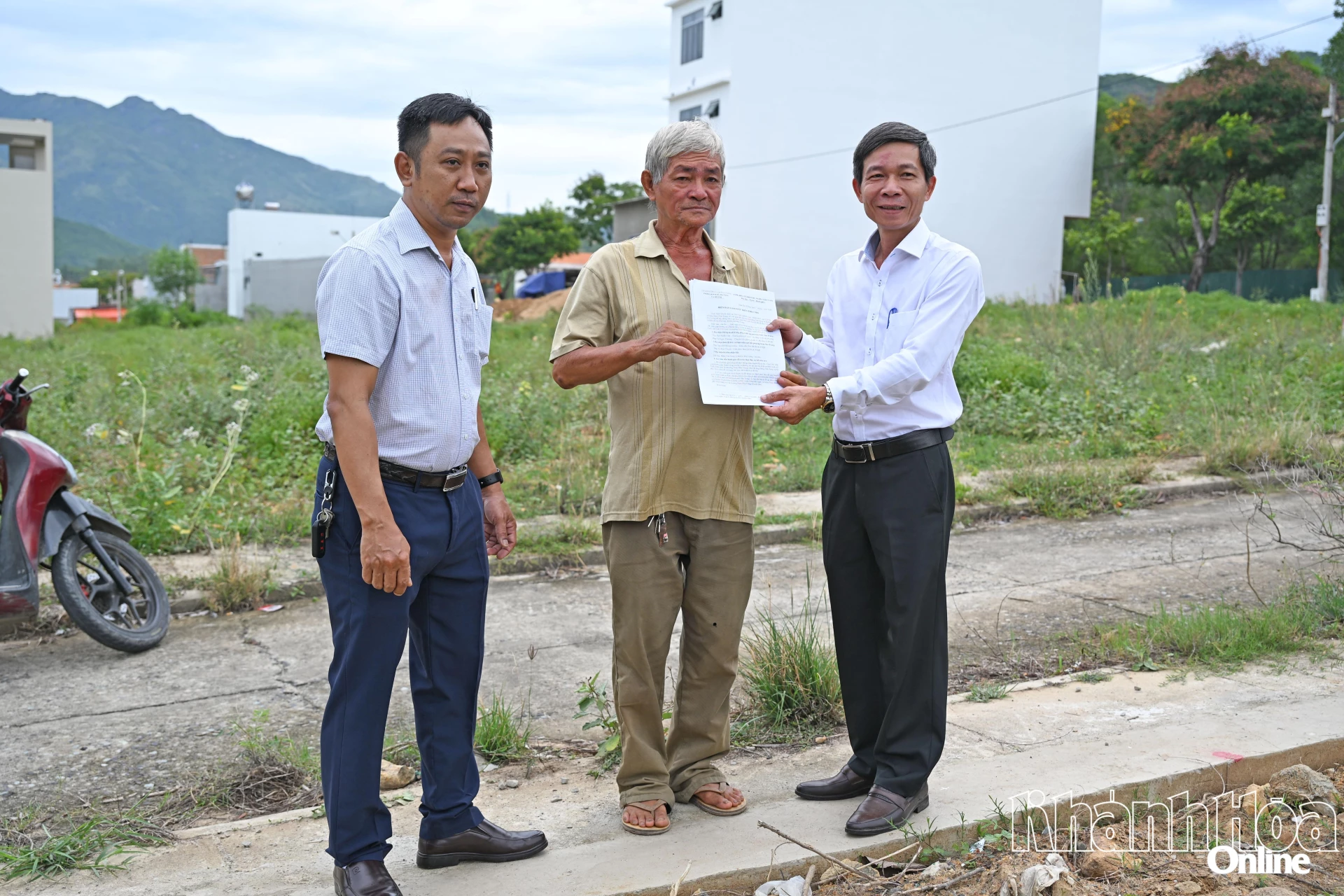 Chủ tịch UBND phường Nguyễn Văn Minh trao biên bản giao đất trên thực địa cho ông Đặng Văn Sang.

