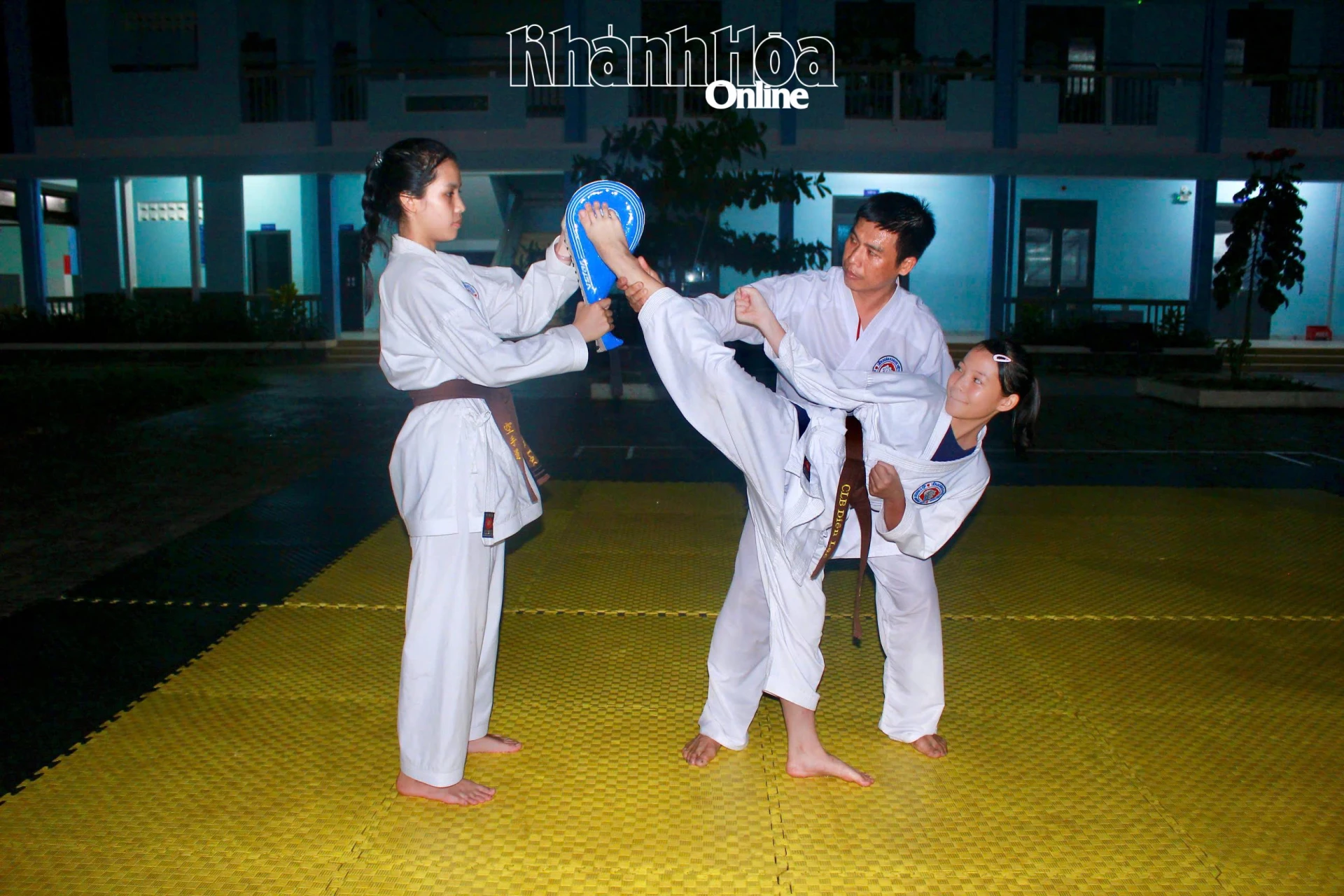Huấn luyện viên hướng dẫn thực hiện kỹ thuật đá cao phối hợp với đích đá cầm tay tại lớp karatedo ở Trường Tiểu học Diên Lạc.