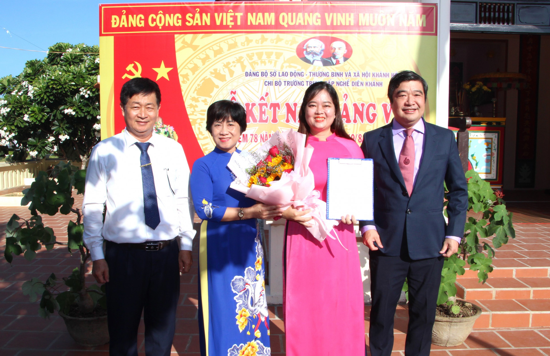 Bà Phạm Thị Khánh Hương - Bí thư Đảng ủy Khối các cơ quan tỉnh và ông Tạ Hồng Quang - Bí thư Đảng ủy, Giám đốc Sở Lao động - Thương binh và Xã hội trao quyết định và tặng hoa chúc mừng Đảng viên mới Văn Thị Bảo Trân.