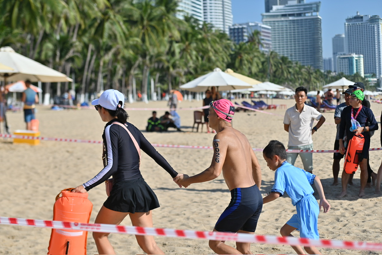 A male swimmer celebrating with his wife and son after finishing the race

