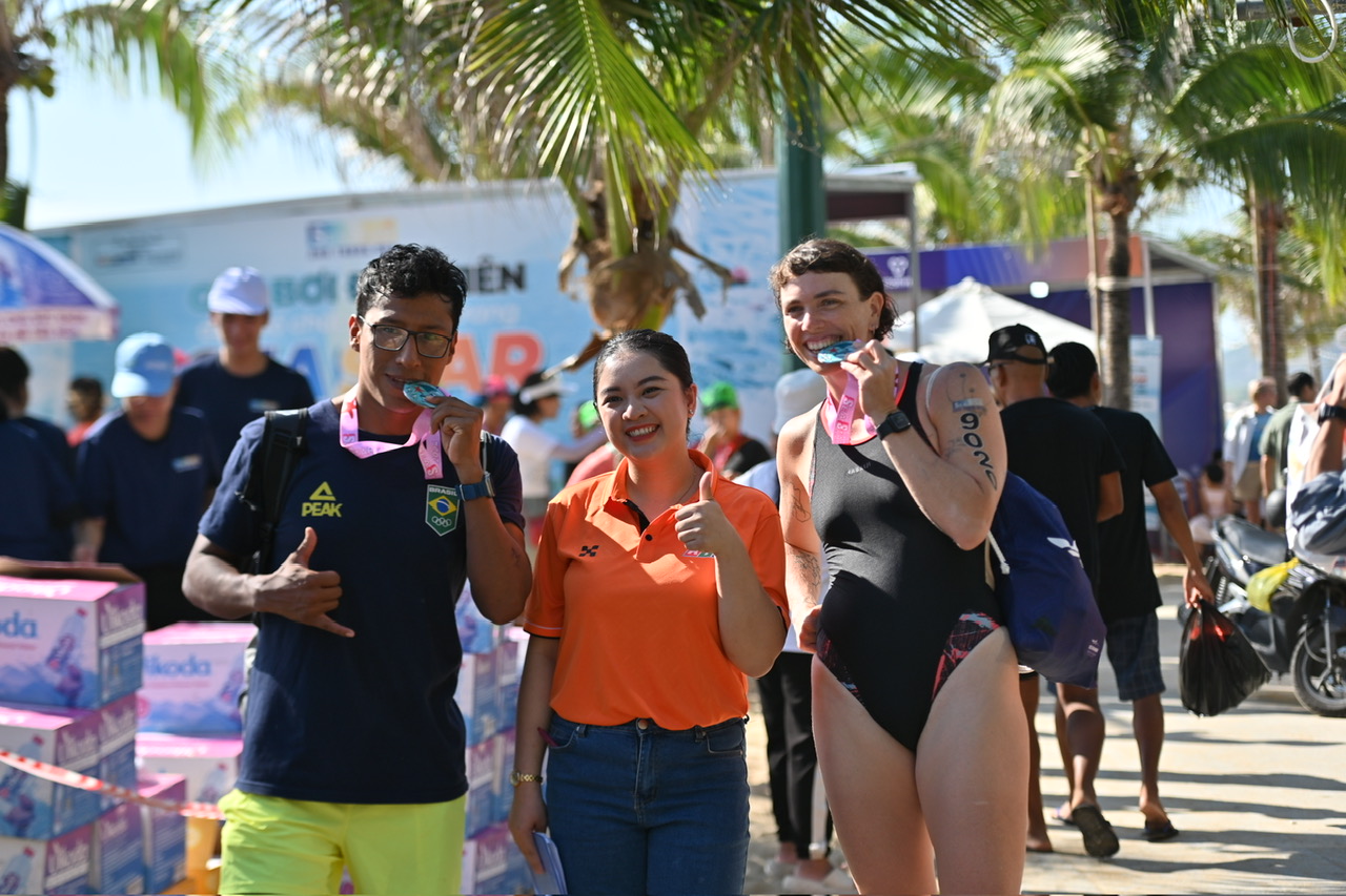 2 foreign swimmers posing for photo with MC Le Hang (middle) of Khanh Hoa Radio and Television Station

