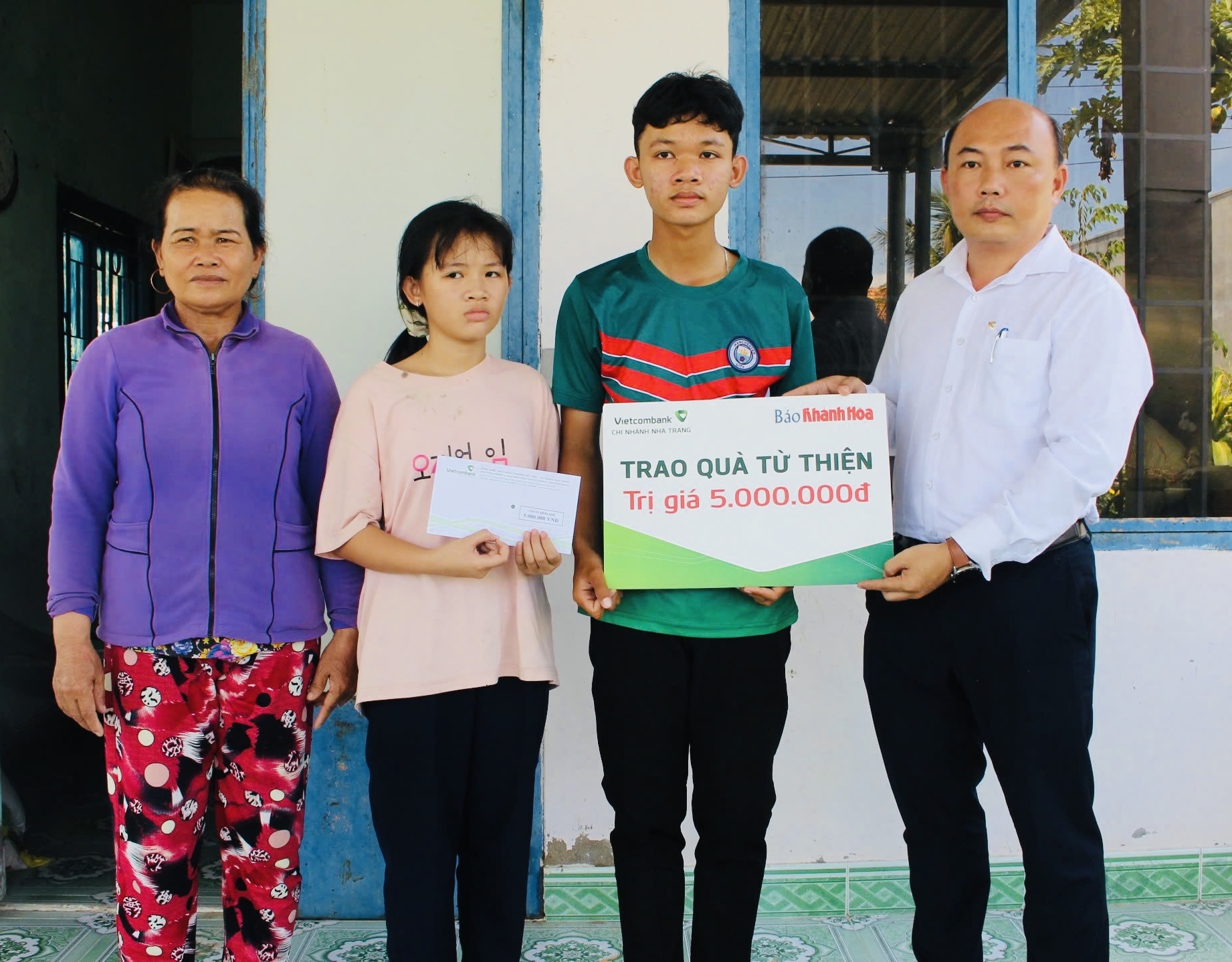Đại diện Vietcombank Nha Trang trao tiền ủng hộ cho 2 anh em Trần Thế Văn và Trần Ái Vy