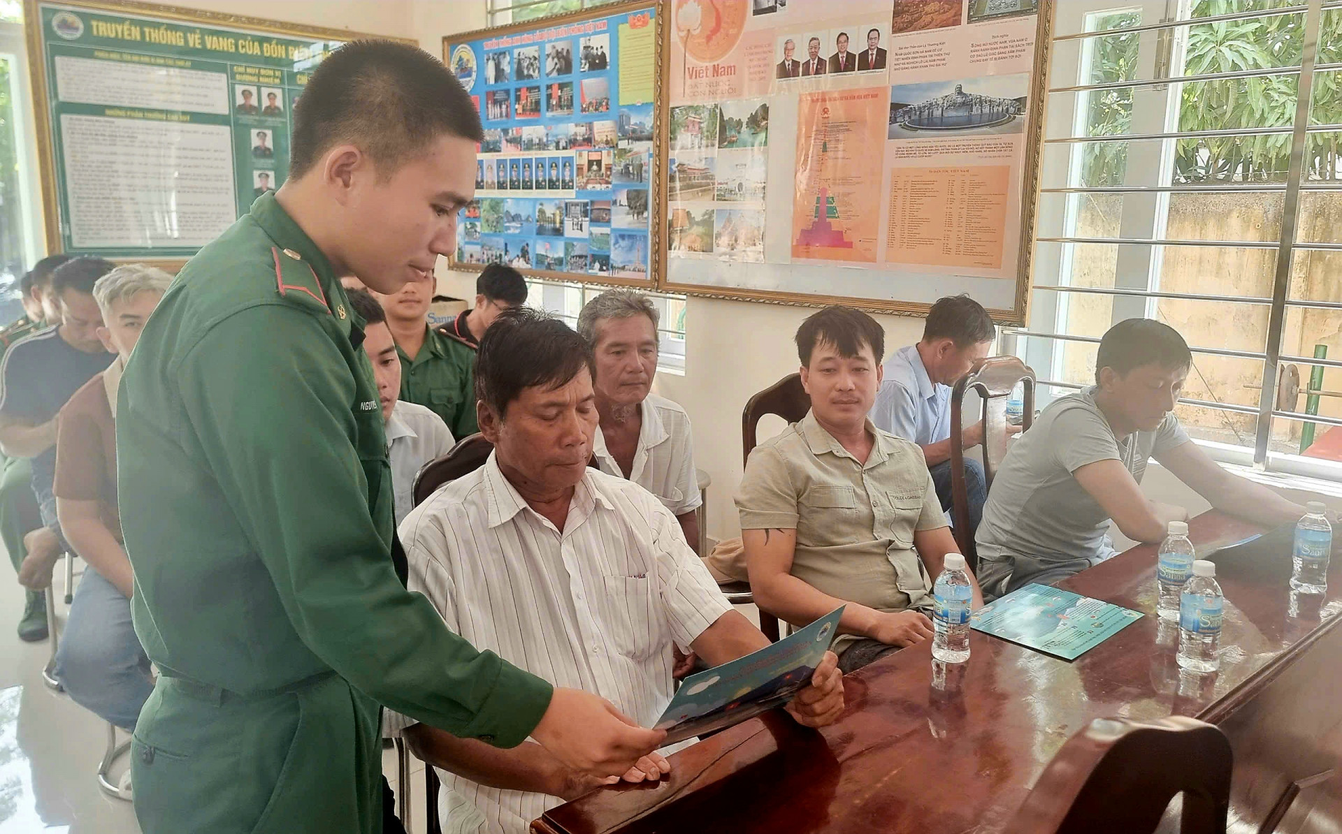 Bộ đội Biên phòng phát tài liệu phổ biến về những hành vi được coi là khai thác thủy sản bất hợp pháp cho ngư dân TP. Cam Ranh. Ảnh: Thúy Hằng.