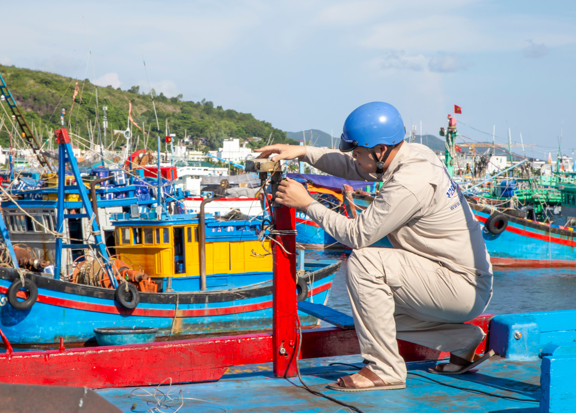 Kỹ thuật viên của Đài Thông tin Duyên hải Nha Trang chỉnh sửa và kẹp chì đối với ăn ten thu phát sóng hệ thống VMS trên tàu cá tại cảng Hòn Rớ (Ảnh C. Định)