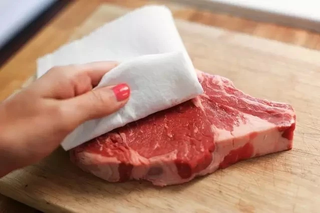 Dùng giấy ăn kiểm tra thịt lợn có bị bơm nước hay không. Ảnh: