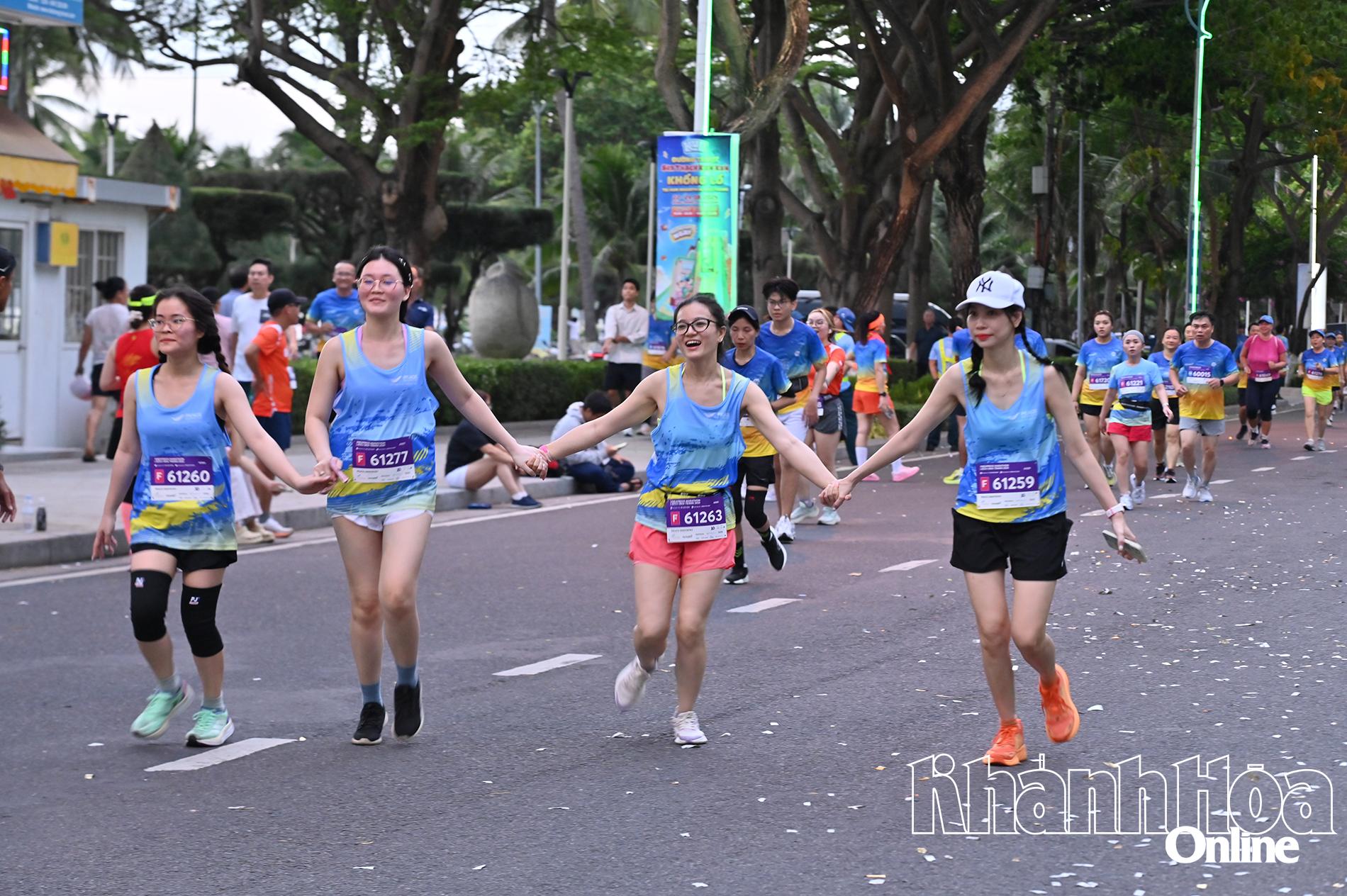 10km runners holding hands running towards the finish line

