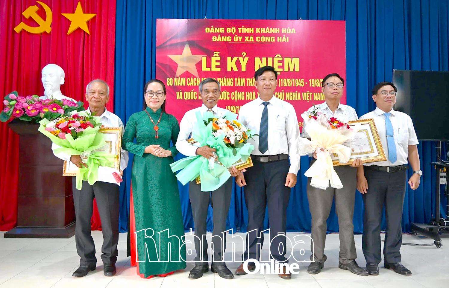 Đồng chí Vũ Thị Thuỳ Trang - Bí thư Đảng ủy, Chủ tịch HĐND xã trao Huy hiệu Đảng và tặng hoa chúc mừng các đảng viên.