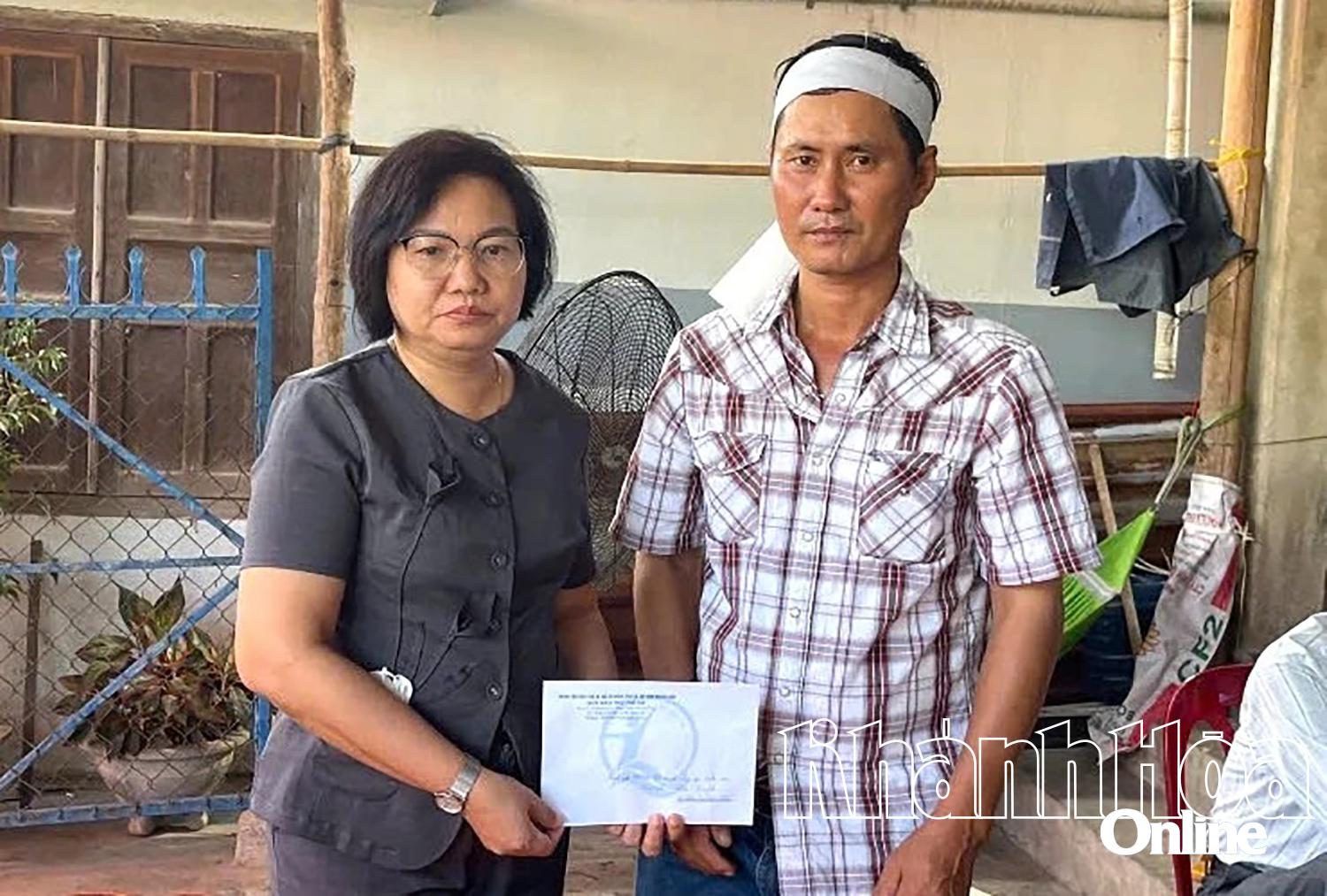 Bà Nguyễn Đình Hồng Loan - Giám đốc Trung tâm Bảo trợ xã hội và Công tác xã hội tỉnh (bên trái) trao hỗ trợ cho gia đình em Nguyễn Nhật Quỳnh.