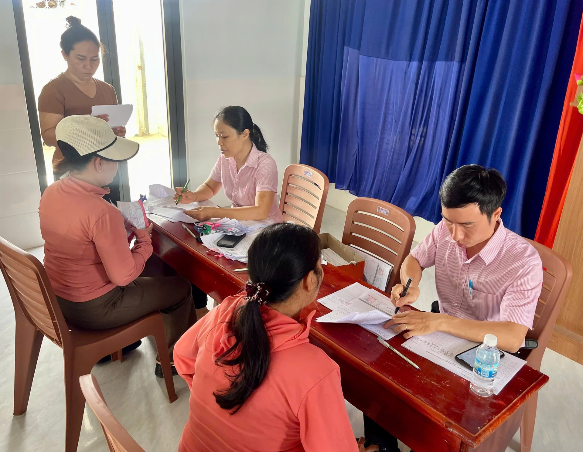 Nhân viên NHCSXH Cam Ranh và khách hàng đối chiếu dư nợ.