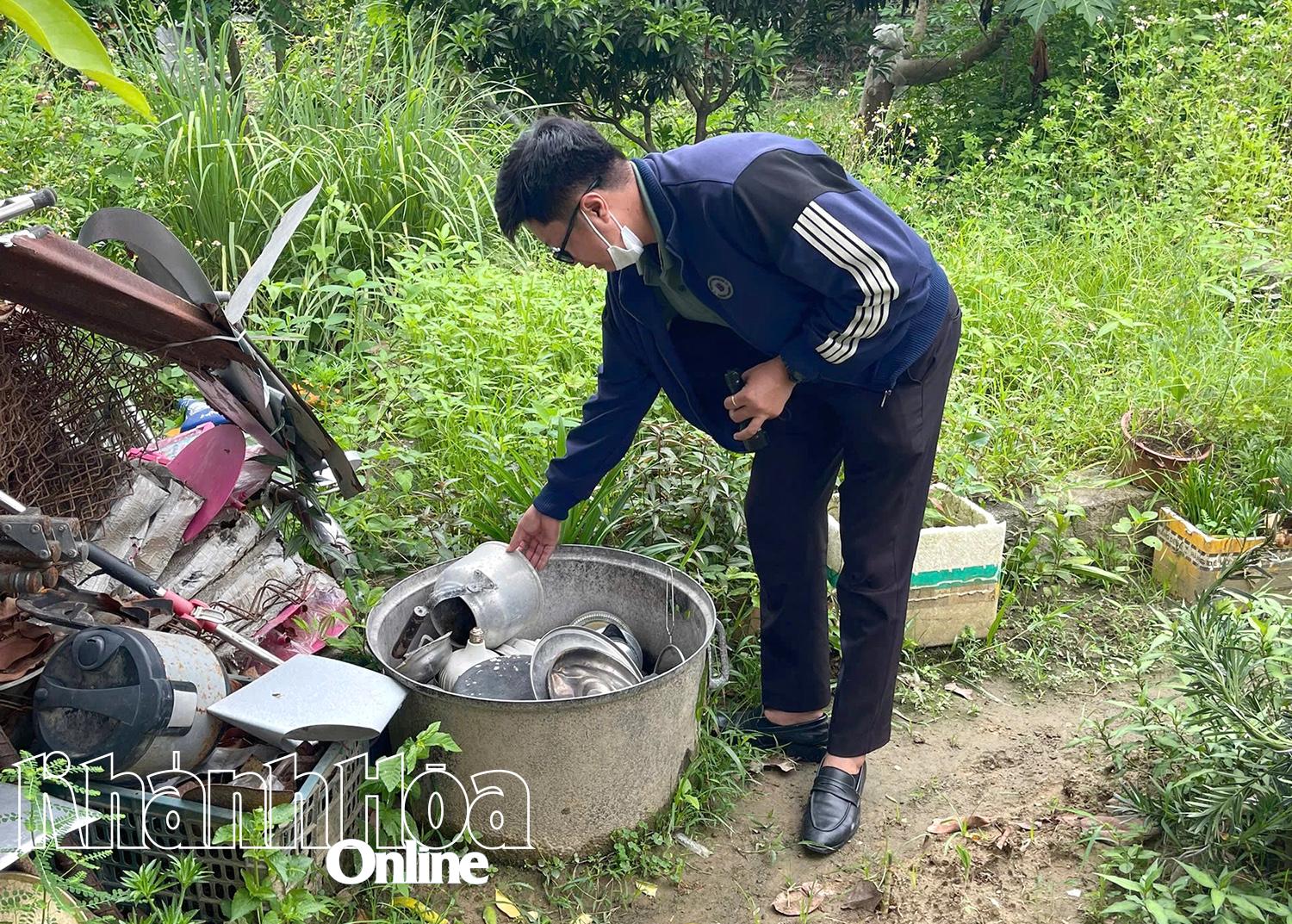 Cán bộ y tế đang lập úp các dụng cụ chứa nước ở ngoài vườn của hộ dân