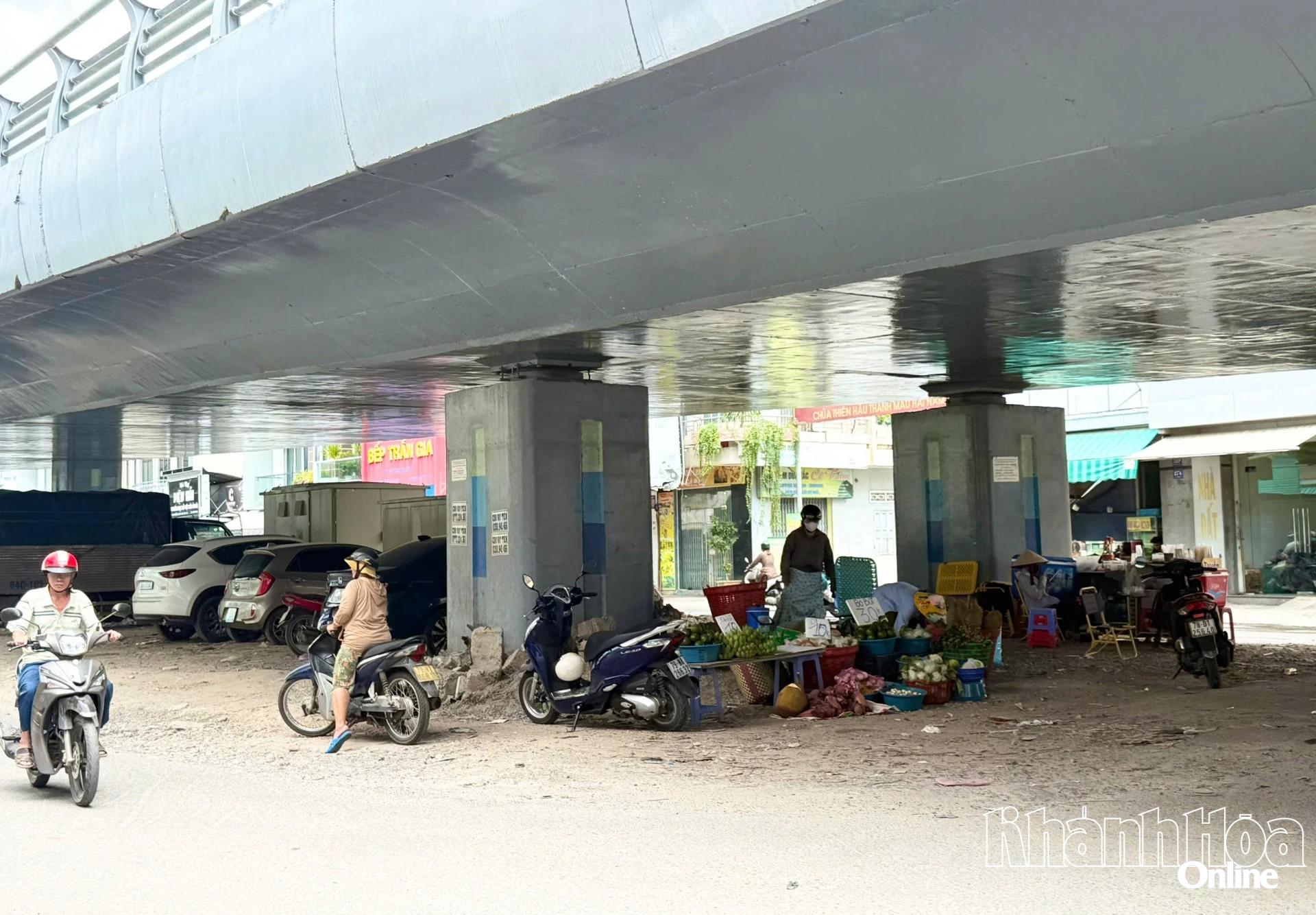 Tại gầm cầu nằm giữa 2 đường gom tầng mặt đất vẫn còn tình trạng người dân buôn bán trái cây, đậu xe ô tô, xe máy tràn lan.