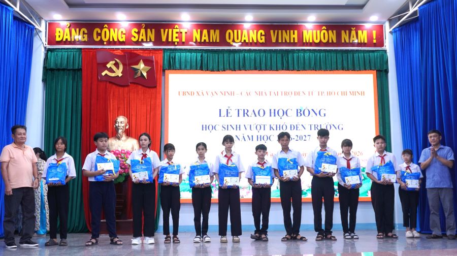 Lãnh đạo xã Vạn Ninh và nhà tài trợ trao học bổng và quà cho các em học sinh.