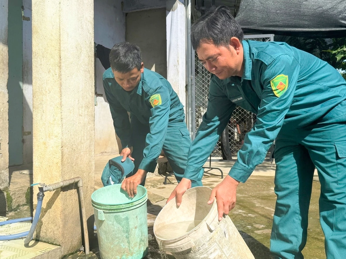 Lực lượng dân quân kiểm tra các dụng cụ chứa nước sinh hoạt của người dân nhằm phát hiện và diệt lăng quăng. Ảnh: PHÙNG QUỲNH
