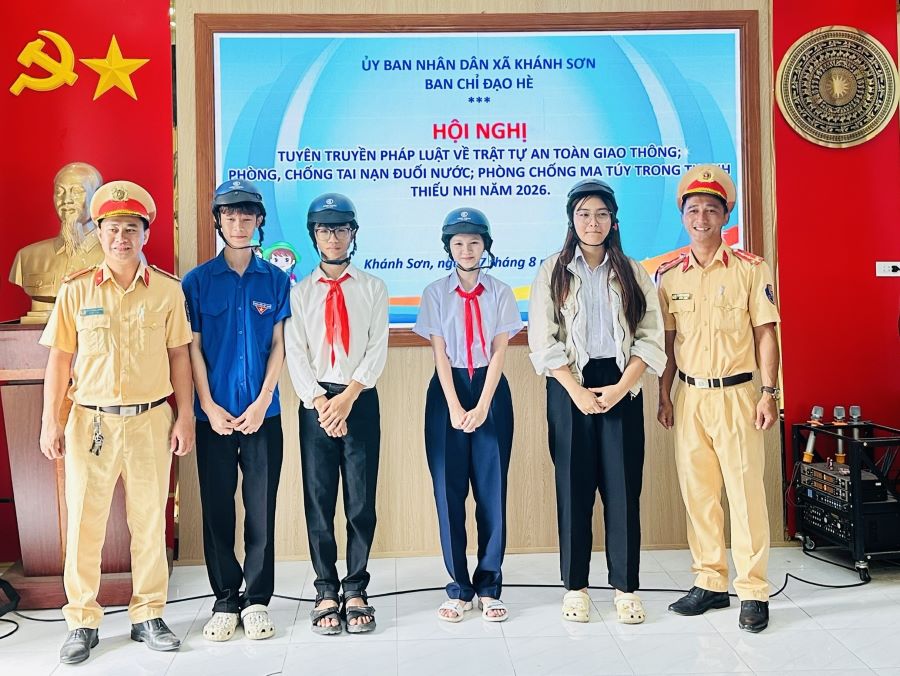 Cán bộ, chiến sĩ công an xã Khánh Sơn trao tặng mũ bảo hiểm cho các em học sinh.