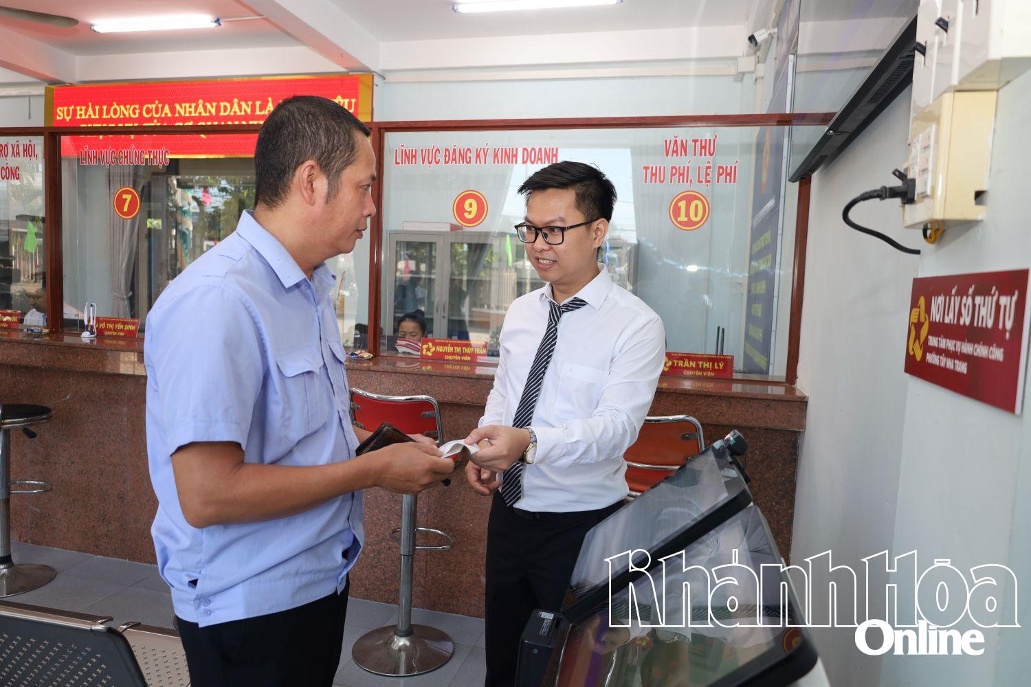 Cán bộ Trung tâm Phục vụ hành chính công phường Tây Nha Trang hỗ trợ người dân lấy số thứ tự tự động. Ảnh: