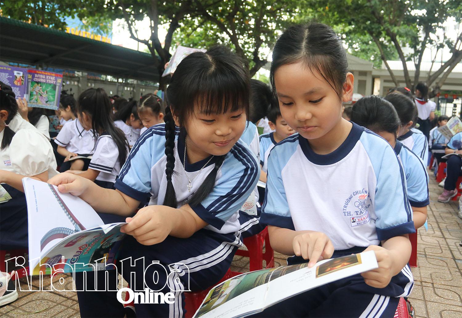 Các em học sinh trao đổi thông tin trong sách.