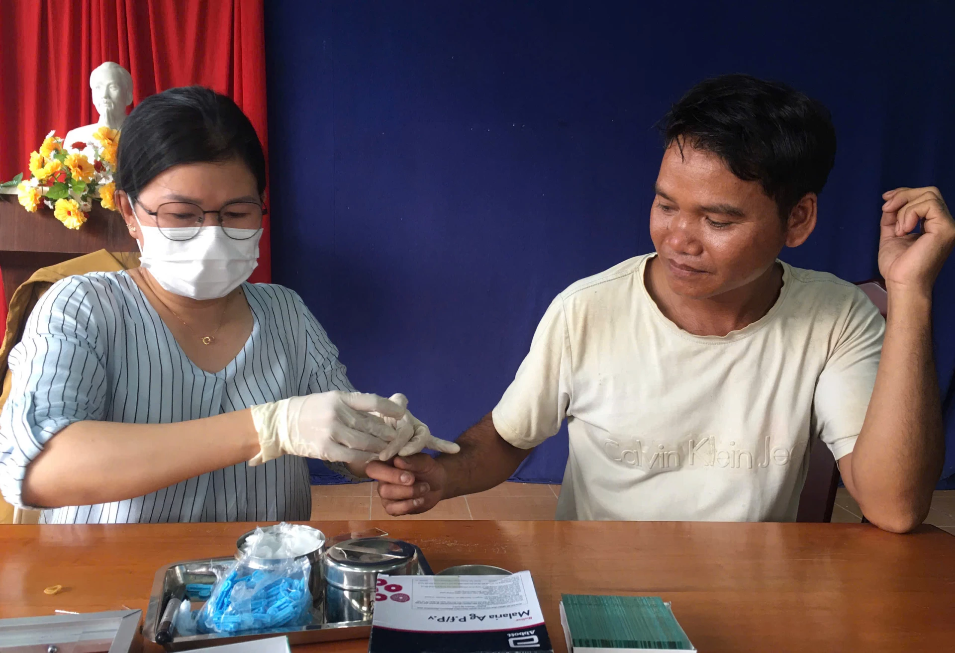 Nhân viên y tế lấy lam máu xét nghiệm ký sinh trùng sốt rét cho người dân.