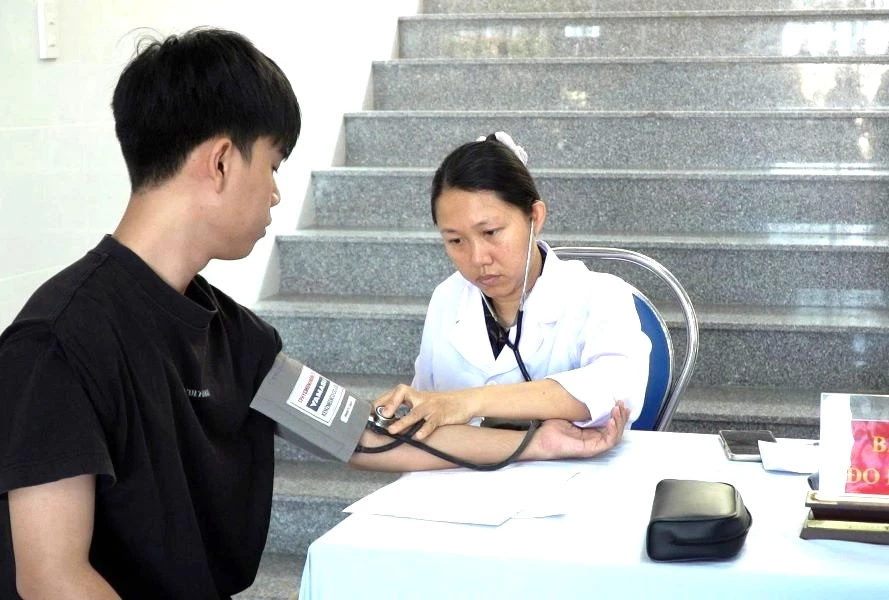 Nhân viên y tế đo huyết áp cho thanh niên.