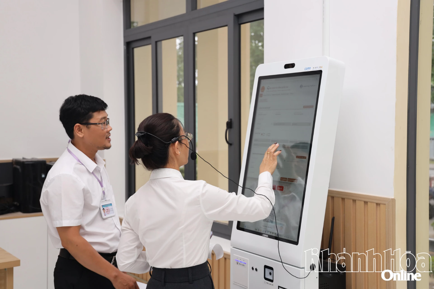 Lãnh đạo Trung tâm Phục vụ hành chính công phường Cam Ranh hướng dẫn người dân sử dụng robot AI để nộp hồ sơ trực tuyến. Ảnh: VĂN KỲ