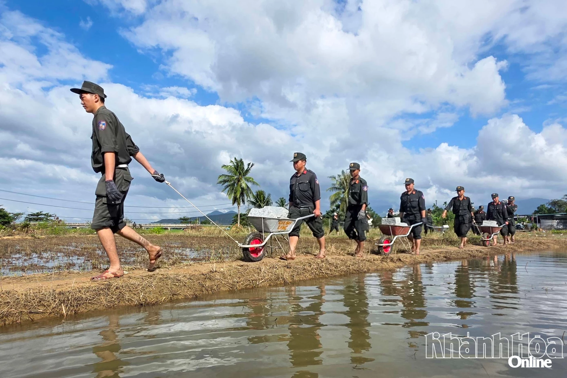 Cán bộ, chiến sĩ Cảnh sát cơ động Công an tỉnh Khánh Hòa vận chuyển vật liệu qua bờ ruộng để xây dựng nhà cho gia đình anh Nguyễn Tấn Lanh ở xã Diên Lạc trong những ngày đầu triển khai Chiến dịch Quang Trung.