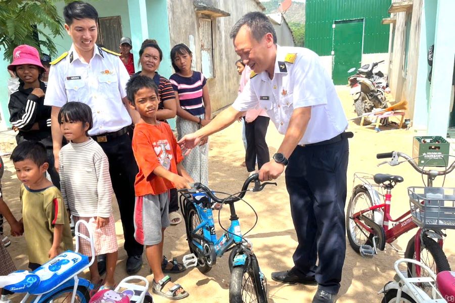 Đồng chí Thiếu tá Phạm Phú Khánh, Trợ lý Khu đô thị Căn cứ quân sự Cam Ranh cùng nhân viên Ban Quản lý Khu đô thị trao tặng xe đạp cho học sinh Làng đồng bào dân tộc thuộc tổ dân phố Quảng Phúc (phường Bắc Cam Ranh).