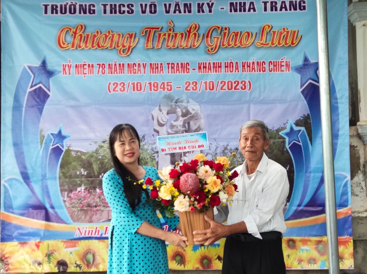 Cô Lê Thị Trang - Hiệu trưởng Trường THCS Võ Văn Ký tặng hoa cho ông Võ Văn Thanh - cháu ruột liệt sĩ Võ Văn Ký. 