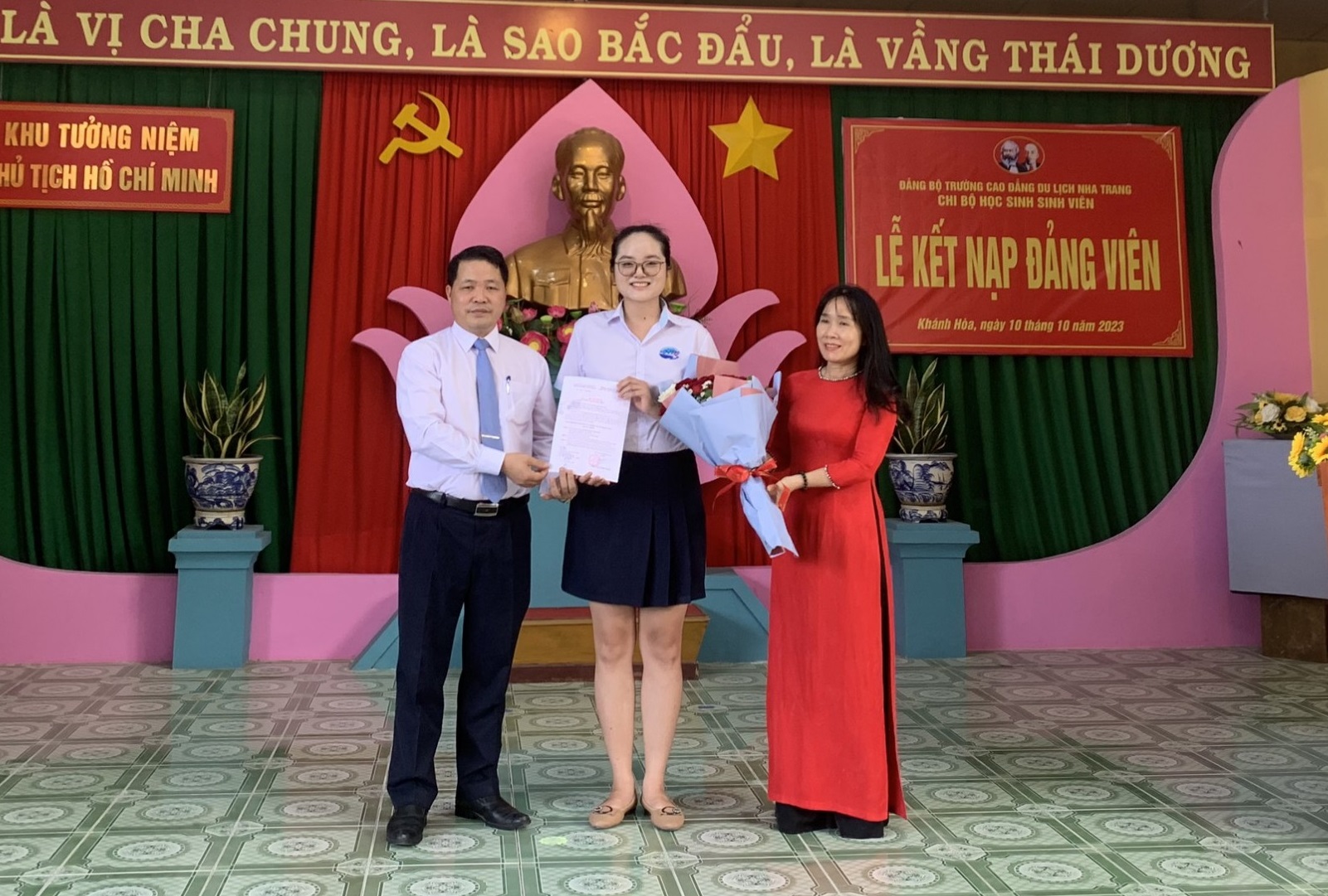 Đồng chí Nguyễn Thị Bích Liên và Bí thư Đảng ủy trường trao quyết định kết nạp và tặng hoa chúc mừng cho đảng viên mới. 