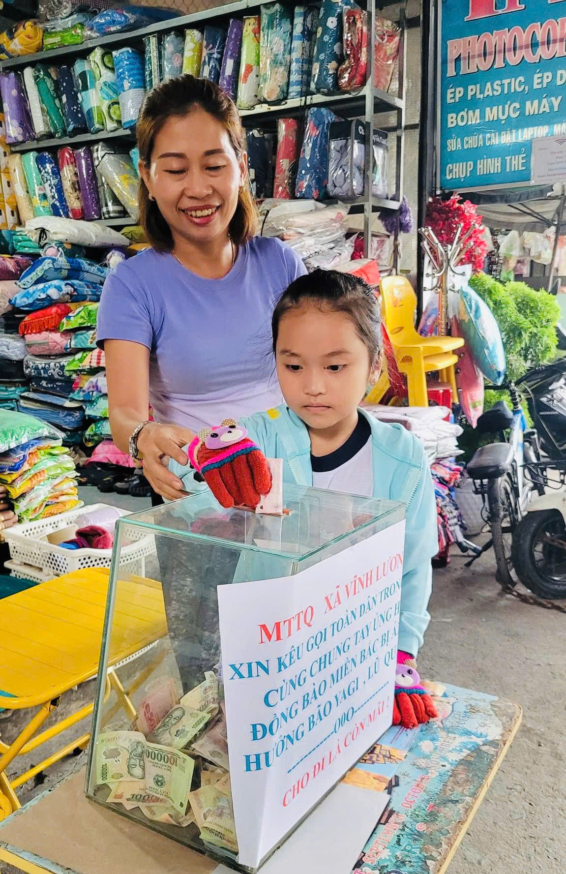 Một em ủng hộ vào thùng quyên góp được Mặt trận xã đặt tại chợ Vĩnh Lương