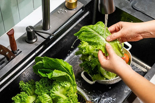 Rửa rau lá nhẹ nhàng dưới vòi nước chảy. (Ảnh: iStock)