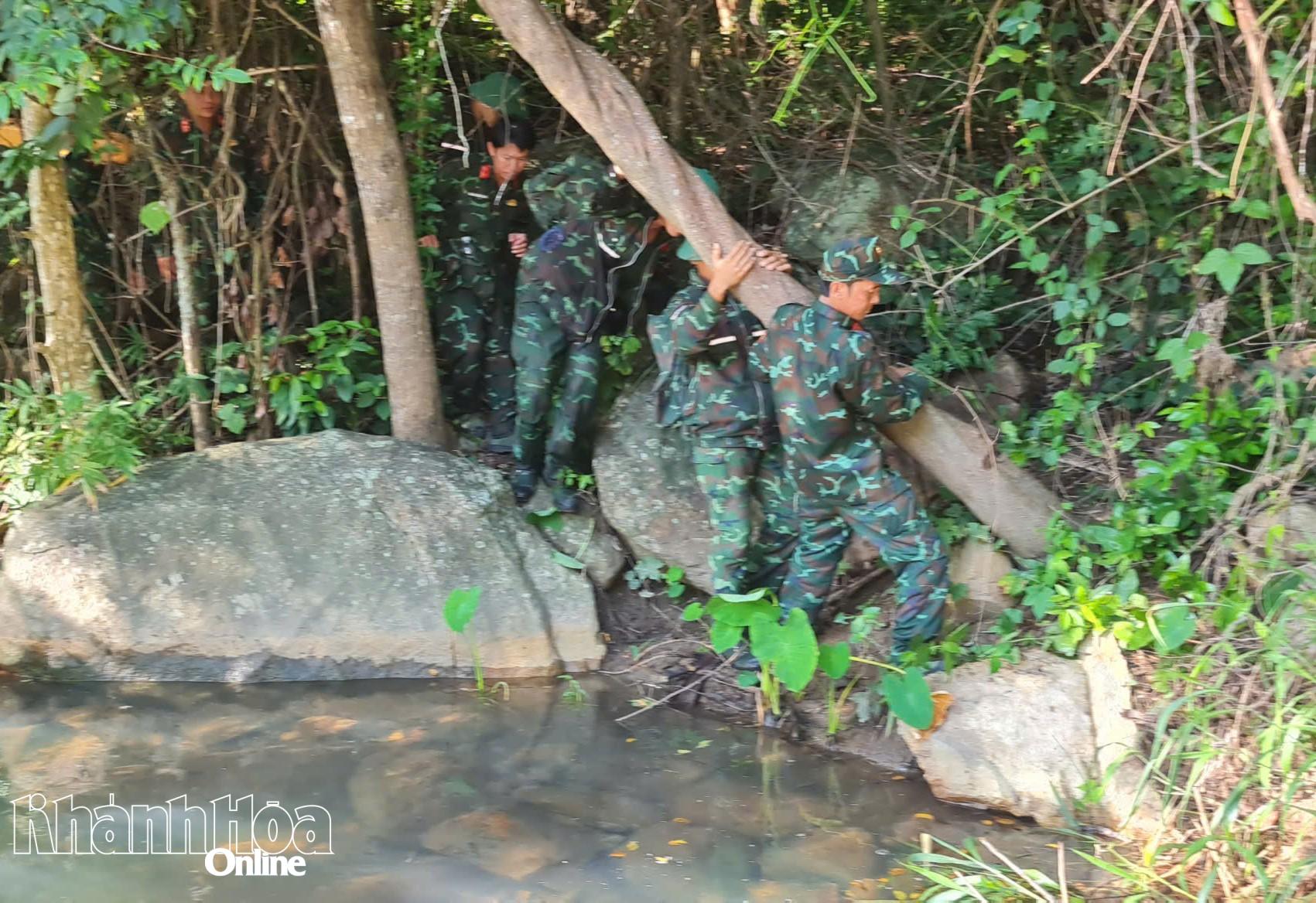 Cán bộ, chiến sĩ cẩn thận vượt qua một con suối ở lưng chừng núi.