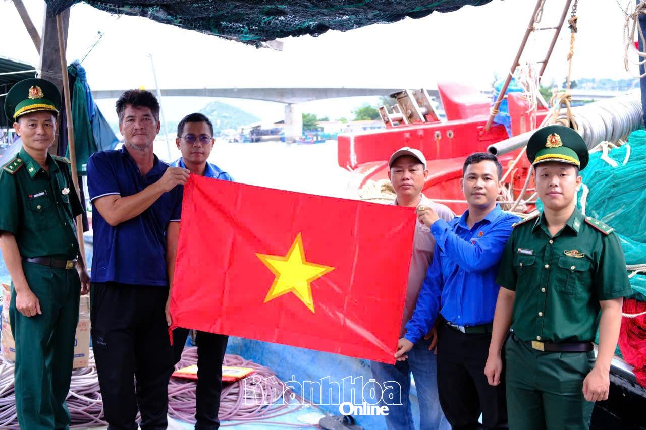 Cán bộ Bộ đội Biên phòng cùng đoàn viên, thanh niên tặng cờ Tổ quốc cho ngư dân.