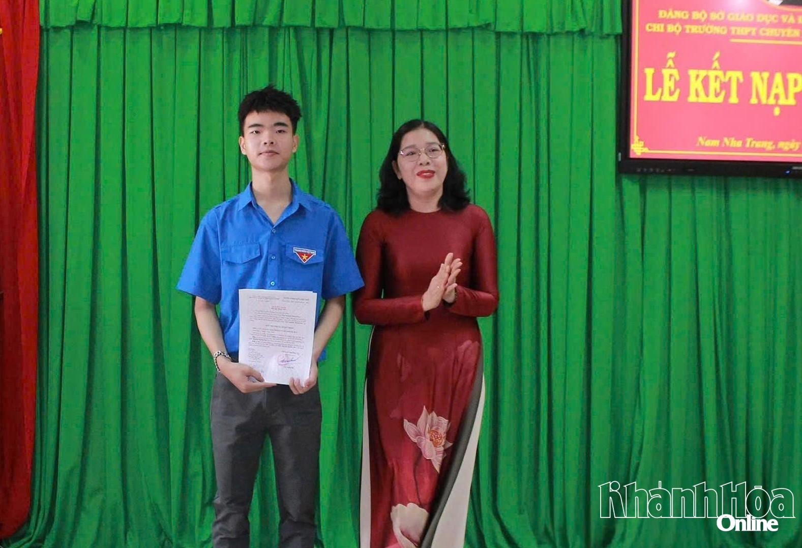 Cô Đặng Ngọc Lệ Thy trao quyết định kết nạp đảng viên mới cho em Trần Nguyễn Khánh Duy.
