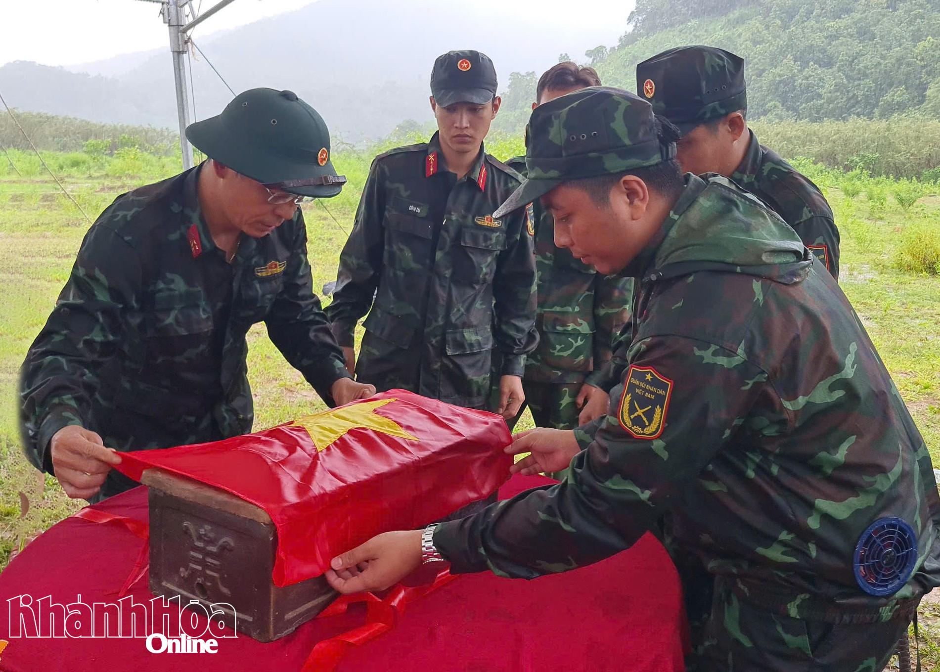 Cán bộ, chiến sĩ trang trọng phủ Quốc kỳ bên ngoài quách hài cốt liệt sĩ trước khi di chuyển về nghĩa trang liệt sĩ, chuẩn bị tổ chức lễ viếng, truy điệu và an táng.