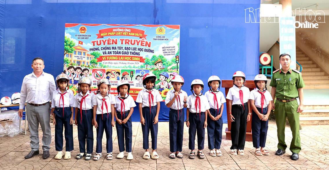 Lãnh đạo xã Cam Hiệp, đại diện Phòng Cảnh sát điều tra tội phạm về ma túy Công an tỉnh trao mũ bảo hiểm cho các em học sinh.