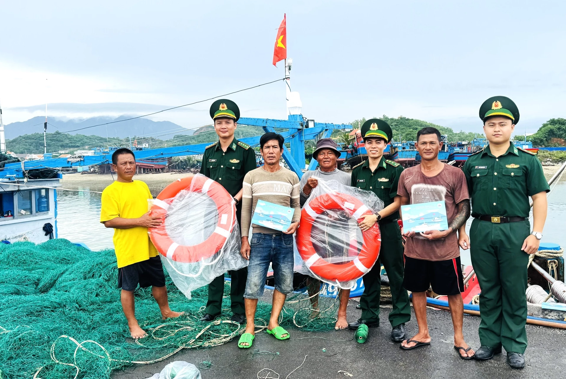 Cán bộ Đồn Biên phòng Ninh Hải phát tờ rơi và trao tặng phao cứu sinh cho ngư dân tại khu neo đậu tránh trú bão Ninh Hải.