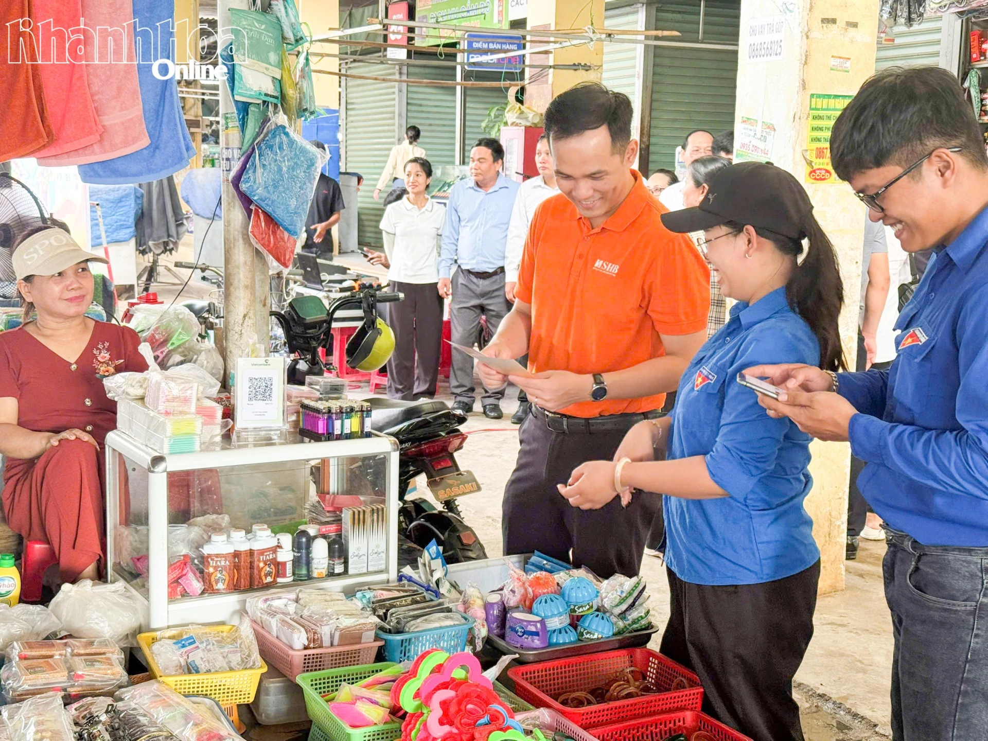 Đại diện các đơn vị hướng dẫn tiểu thương quét mã QR để tiếp cận thông tin và sử dụng các tiện ích số tại Chợ Mới Ninh Quang.