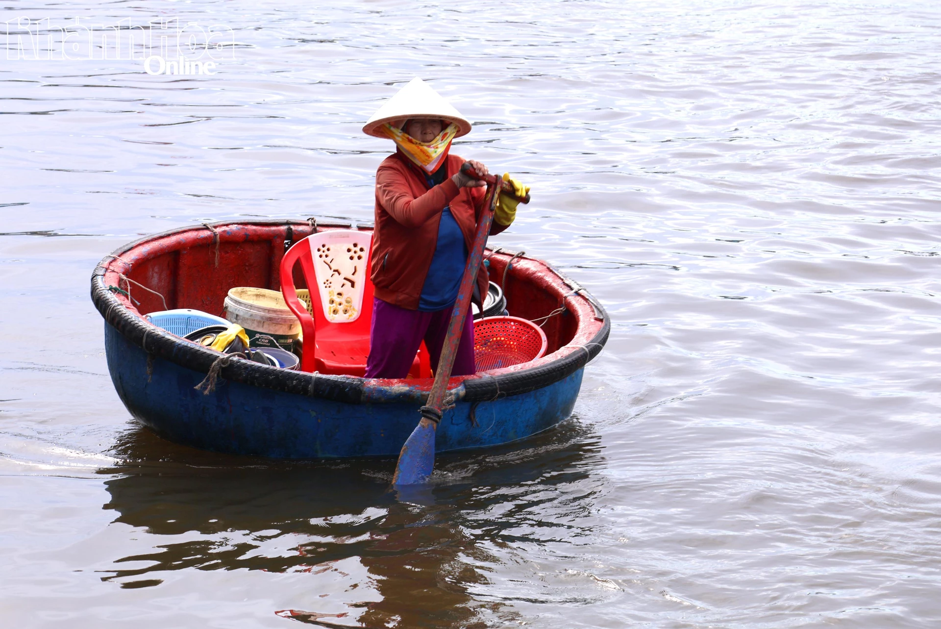 Một người phụ nữ chèo thúng mua cá.