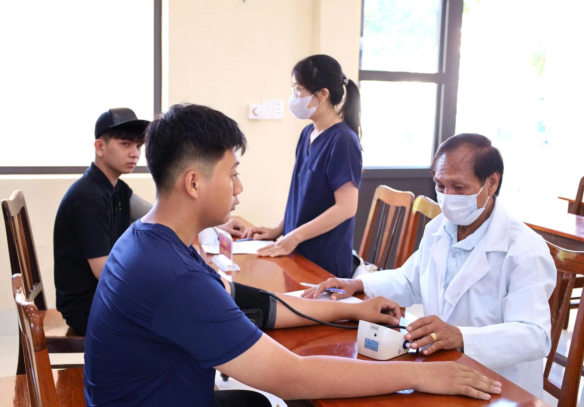 Các y, bác sĩ đo huyết áp cho thanh niên tham gia khám sơ tuyển sức khỏe nghĩa vụ quân sự.
