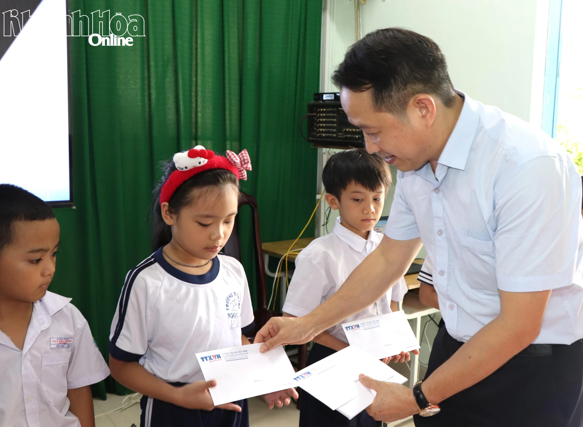 Đại diện Trung tâm Thông tin Thông tấn xã Việt Nam khu vực miền Trung - Tây nguyên tặng quà cho học sinh.