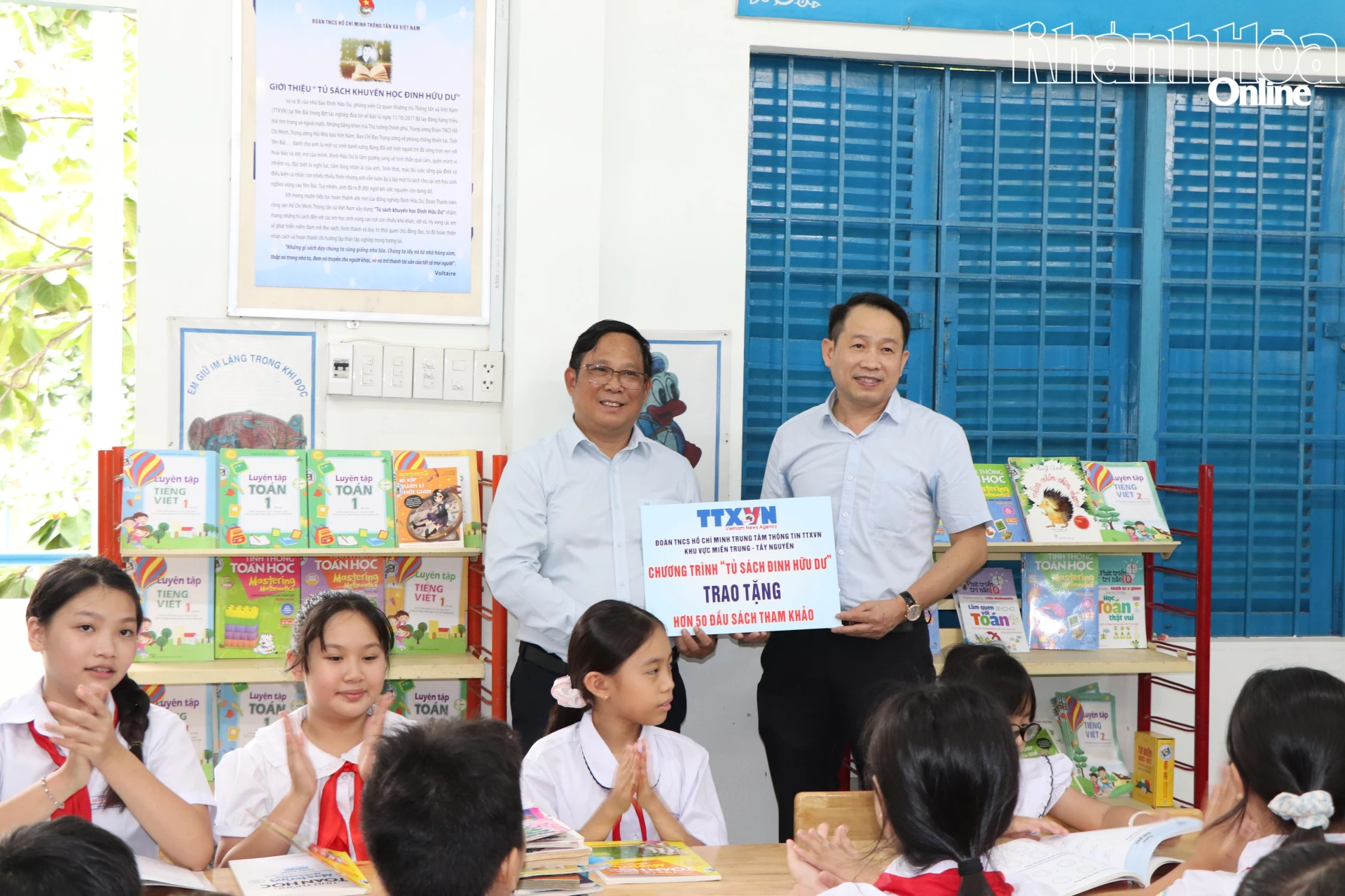 Đại diện Trung tâm Thông tin Thông tấn xã Việt Nam khu vực miền Trung - Tây nguyên (bên phải) trao bảng tượng trưng 50 đầu sách cho lãnh đạo Trường Tiểu học Tây Nha Trang.