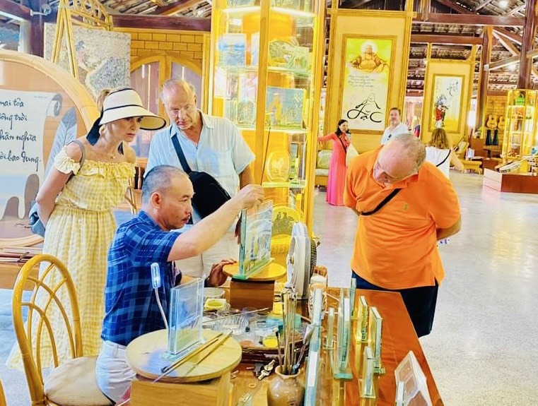 Cruise tourists watch artisans make sand paintings at Truong Son Craft Village.