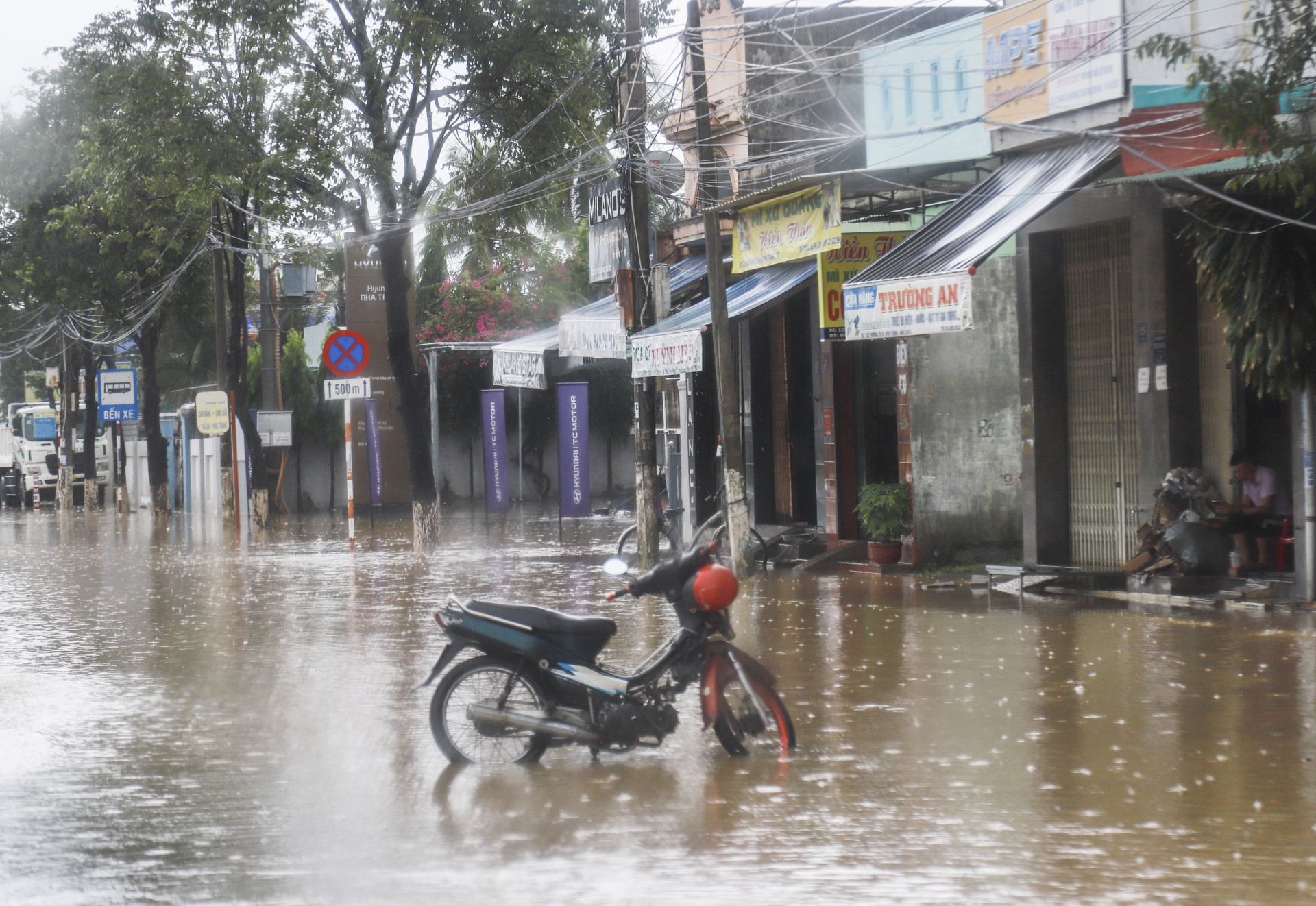 Người dân dùng xe gắn máy cảnh báo nước ngập sâu trên đường 23-10.