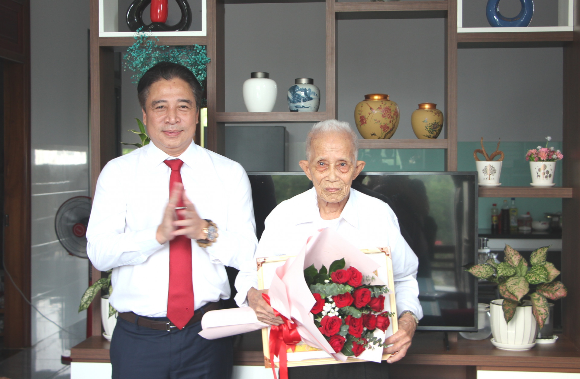 Đồng chí Nguyễn Khắc Toàn trao huy hiệu và tặng hoa chúc mừng đảng viên Lê Văn Giỏi.